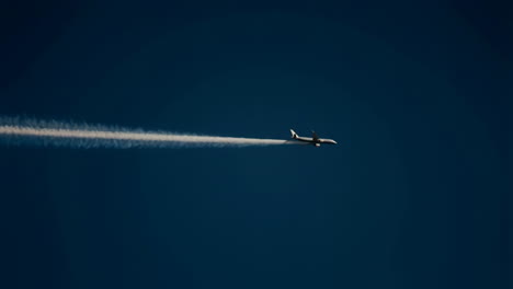 airplane with contrail flying in a deep blue sky