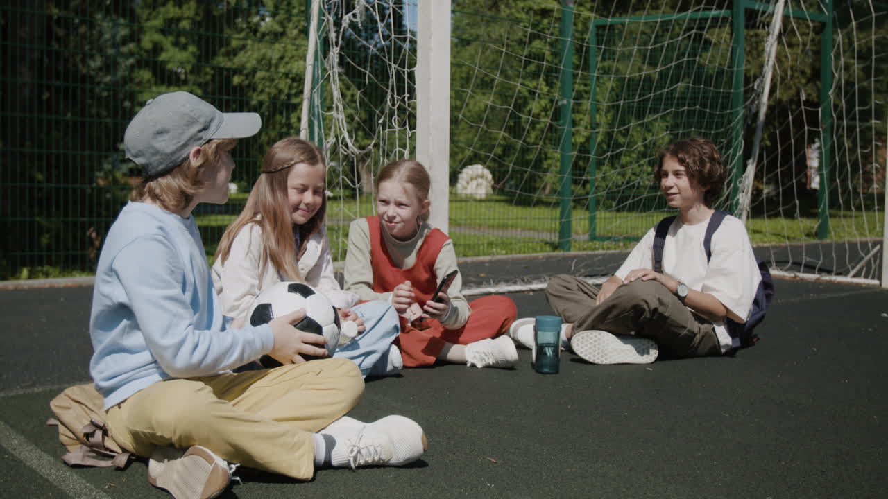 Kids playing and interacting with a soccer ball on an outdoor playground