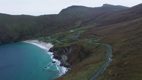 Cinematic-rotating-drone-shot-of-Keem-Beach-and-the-highway-in-Ireland
