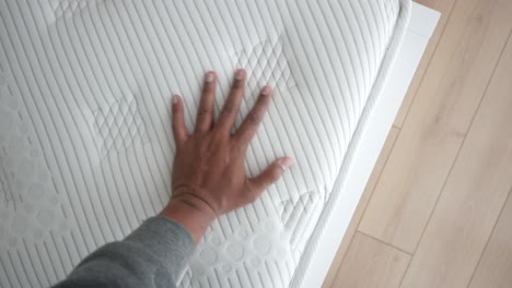 a hand touching a white mattress