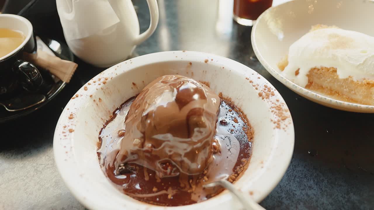 Delicioso profiterol de chocolate con salsa en un acogedor ambiente de cafetería.