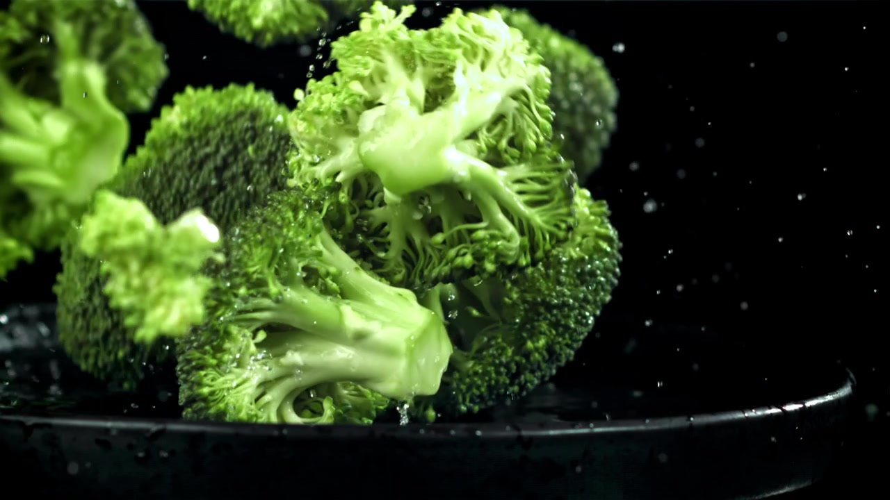 Cimette di broccoli freschi e verdi che cadono nell'acqua al rallentatore