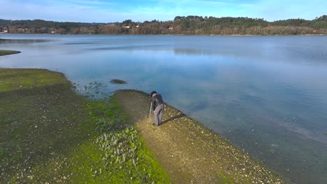 male photographer with camera and tripod taking photos on the lake shore