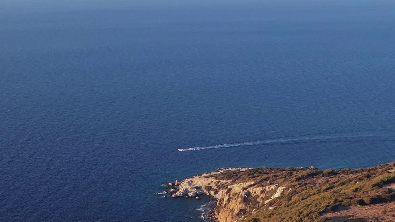 Vista della costa e di una barca a Rodi, in Grecia, sotto un cielo azzurro limpido