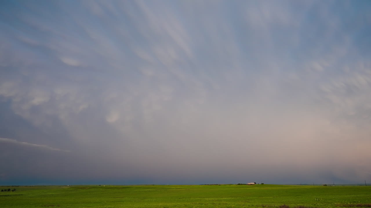 Vast storm cloud with lightning flashes and shifting light across the horizon
