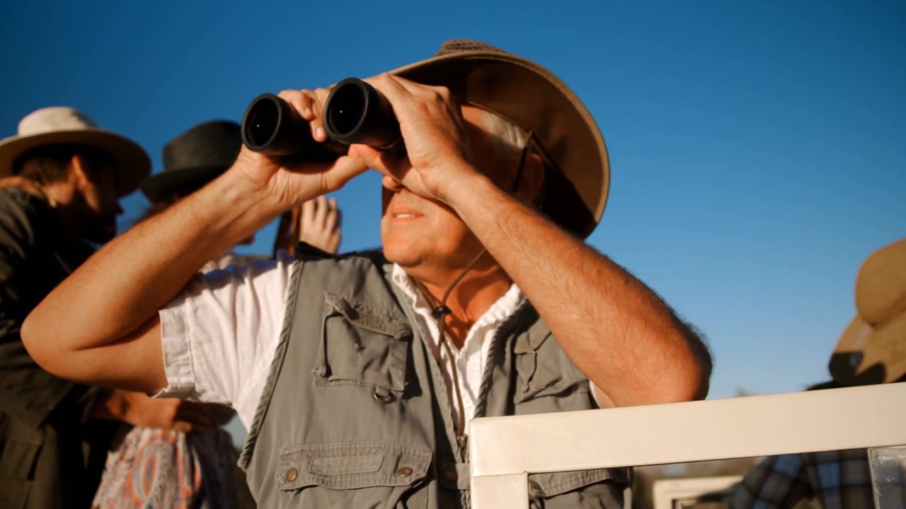 Vertical video: Spotting in sky, scanning man in hat, vest raising binoculars at rail with bubbles