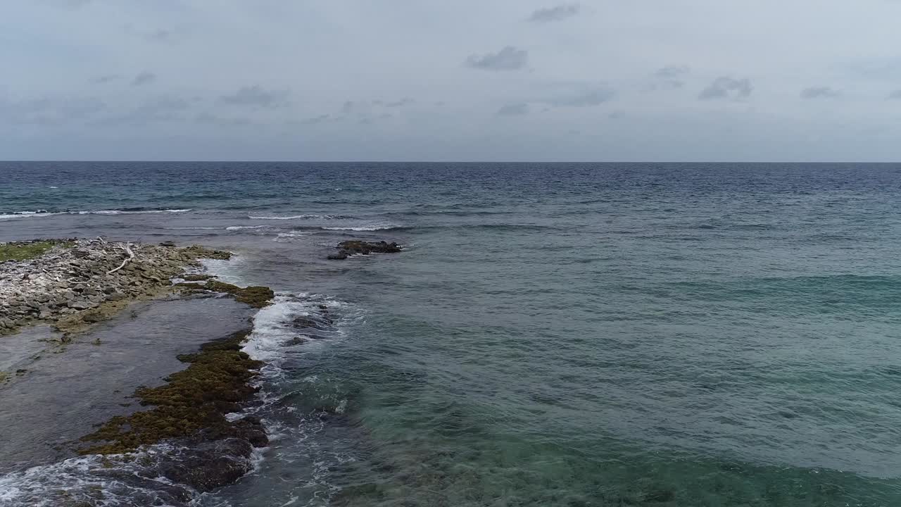 Drone flying over coral rocky coastline waves crashing