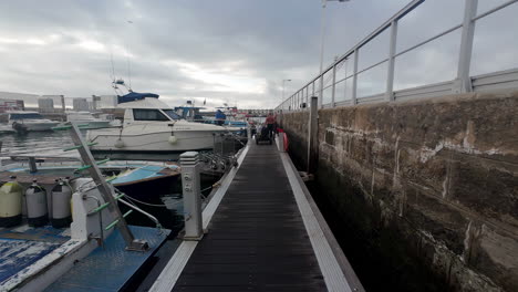 Walking-along-the-Port-of-Tarifa,-past-yachts-and-fishing-boats,-on-a-cloudy-afternoon