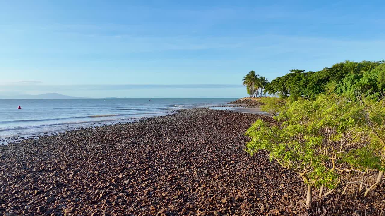 Drone footage captures lush mangroves along a rocky shoreline under clear skies in Port Douglas, Australia