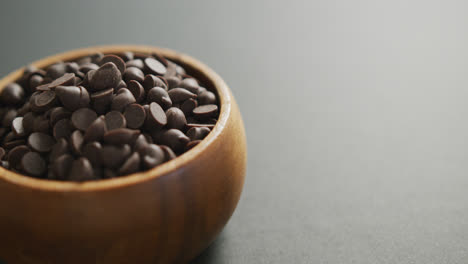 Video-of-close-up-of-wooden-bowl-of-chocolate-chip-over-grey-background