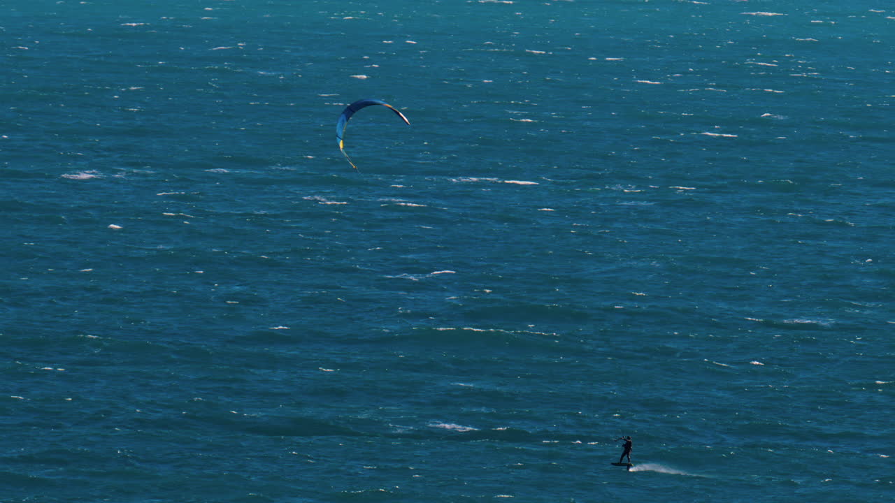 Distant view of a man kitesurfing on a sunny day