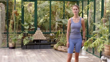 standing in glass house, woman in yoga outfit crossing arms, looking relaxed, copy space