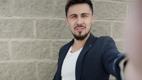 man taking a selfie in front of brick wall