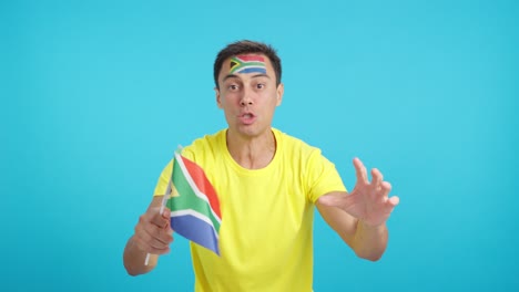 man cheering for south africa screaming and waving a national flag