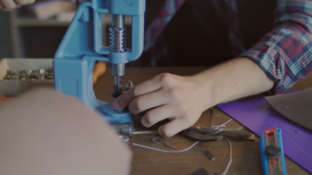 производитель кожи вставляет металлическую кнопку в пояс.