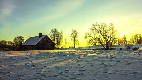 snowy landscape with a wooden house or cabin under a golden and blue sky at sunset