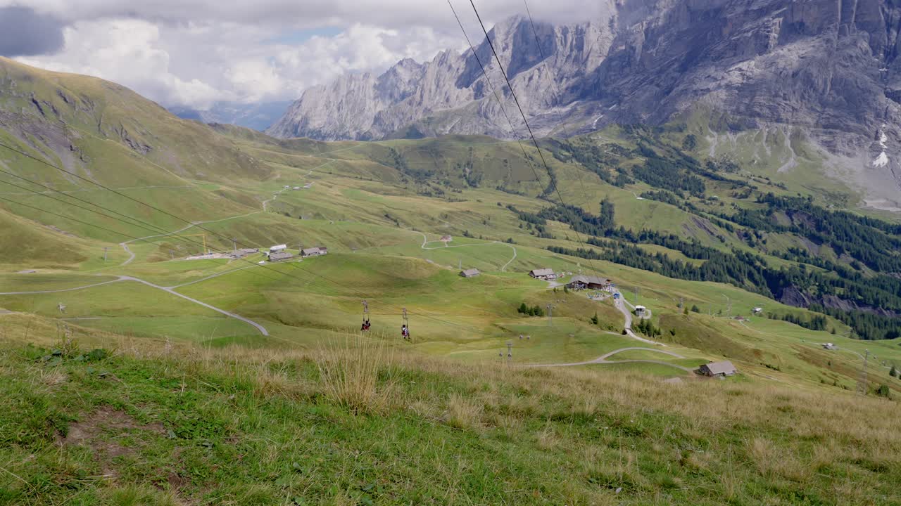 dos personas bajando una colina en tirolesa en grindelwald primero en suiza