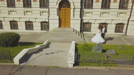 newly wedded couple dances at modern building upper view