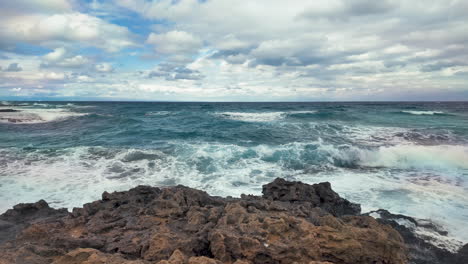 una escena costera en chipre con olas chocando contra la orilla rocosa