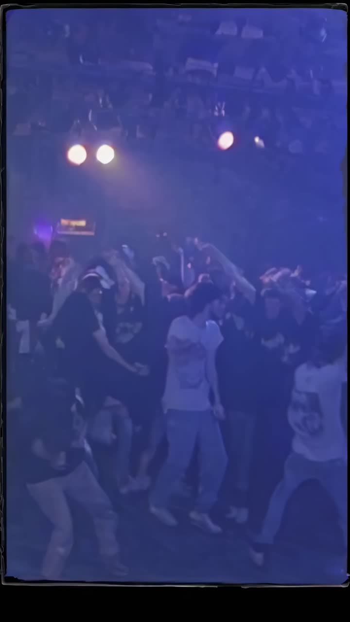 Dynamic video still of a concert crowd from a low angle, capturing energetic movement and excitement