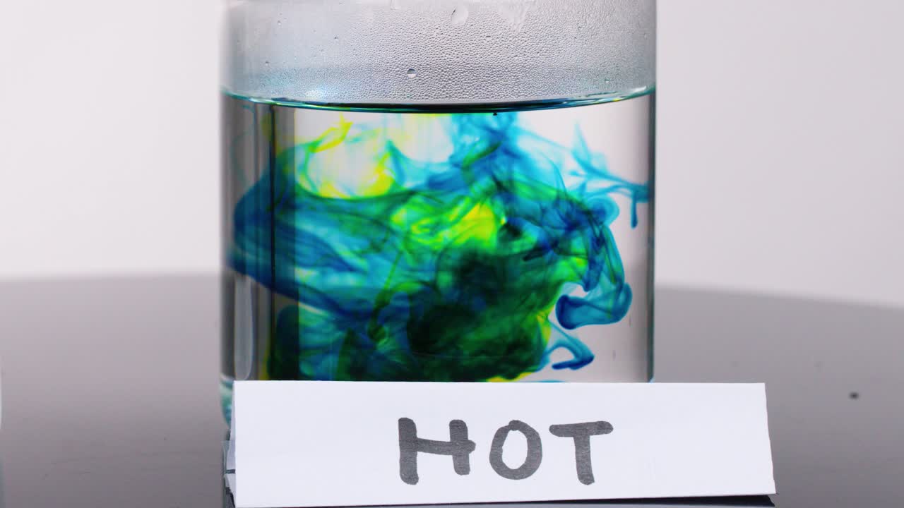 Colored dye disperses rapidly in hot water, demonstrating thermal convection and molecular motion, studio lighting