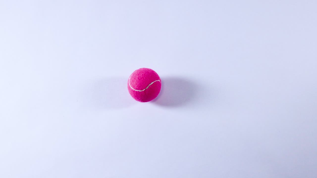 una pelota de tenis rosa rebotando en una superficie blanca