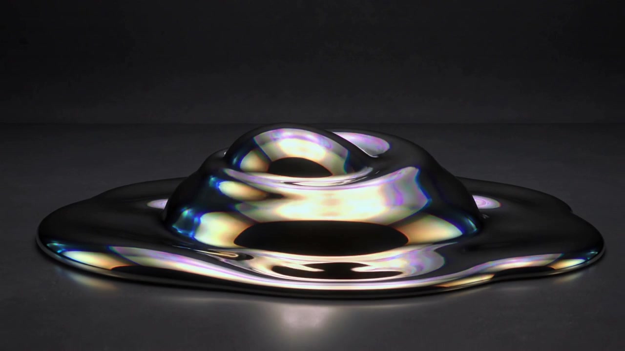 Goccioline che si scontrano causando la fusione di liquido metallico in una pozzanghera sul tavolo sotto la luce dello studio per tensione.