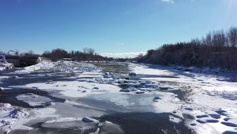winter river system is half frozen on beautiful sunny day with fresh snow low flight