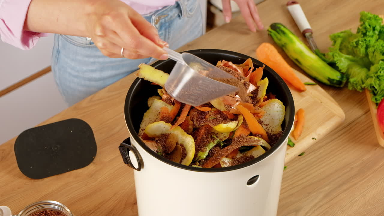 Woman recycling organic waste by pouring Bokashi bran on the vegetable peels. in the kitchen
