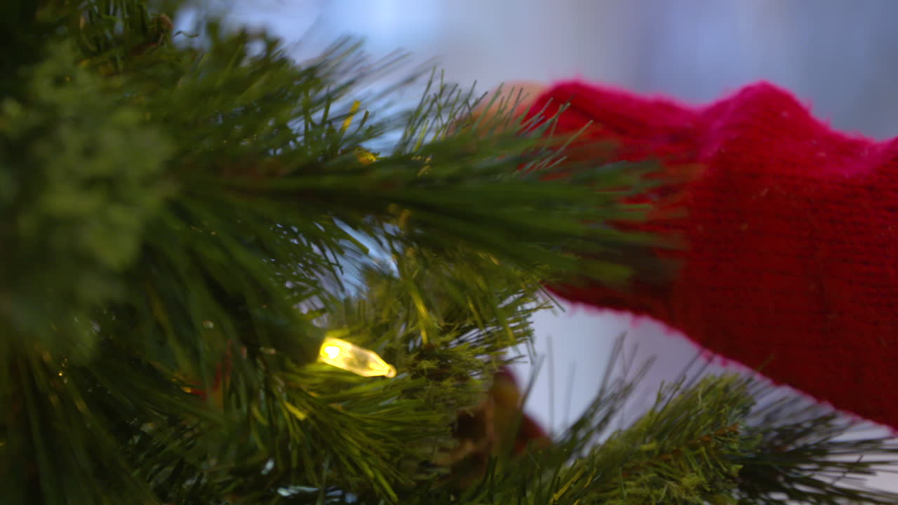 крупным планом кадры руки ребенка, когда он вешает украшение на рождественскую елку