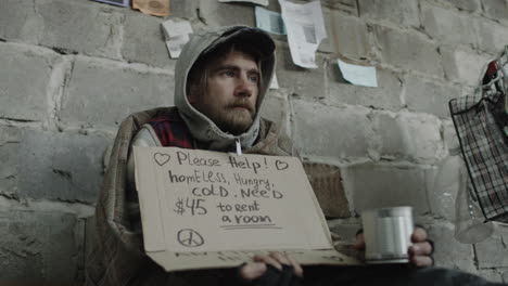 homeless man begging for help with a cardboard sign