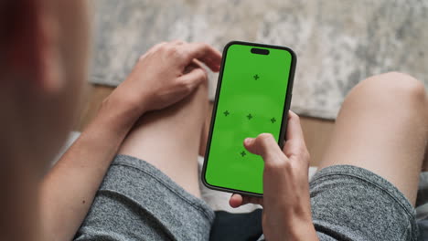 person using a smartphone with a green screen