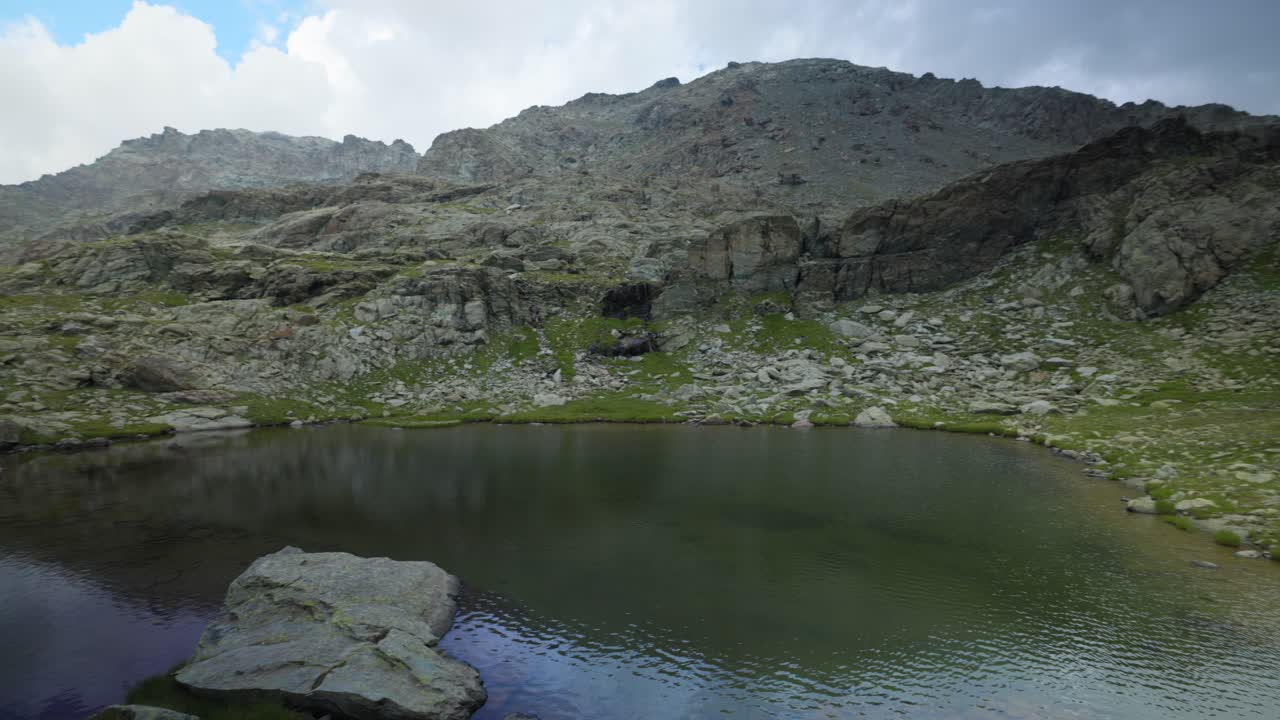 fotografía idílica de una mujer apuntando a un pequeño estanque pacífico en las montañas de valmalenco, italia