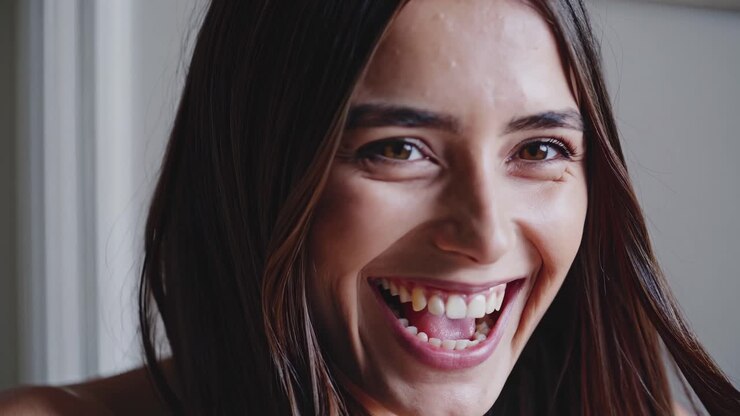 Close-up video shot of a woman laughing joyfully, capturing her expression from a low angle