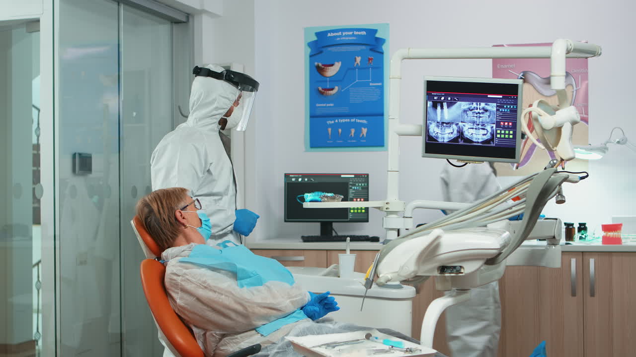 dentista en traje general mostrando la situación del paciente de los dientes rayos x