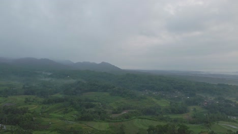 Drohnenflug-über-Indonesische-Landschaft-Mit-Blick-Auf-Grüne-Landwirtschaftliche-Felder-Und-Bewölkten-Himmel