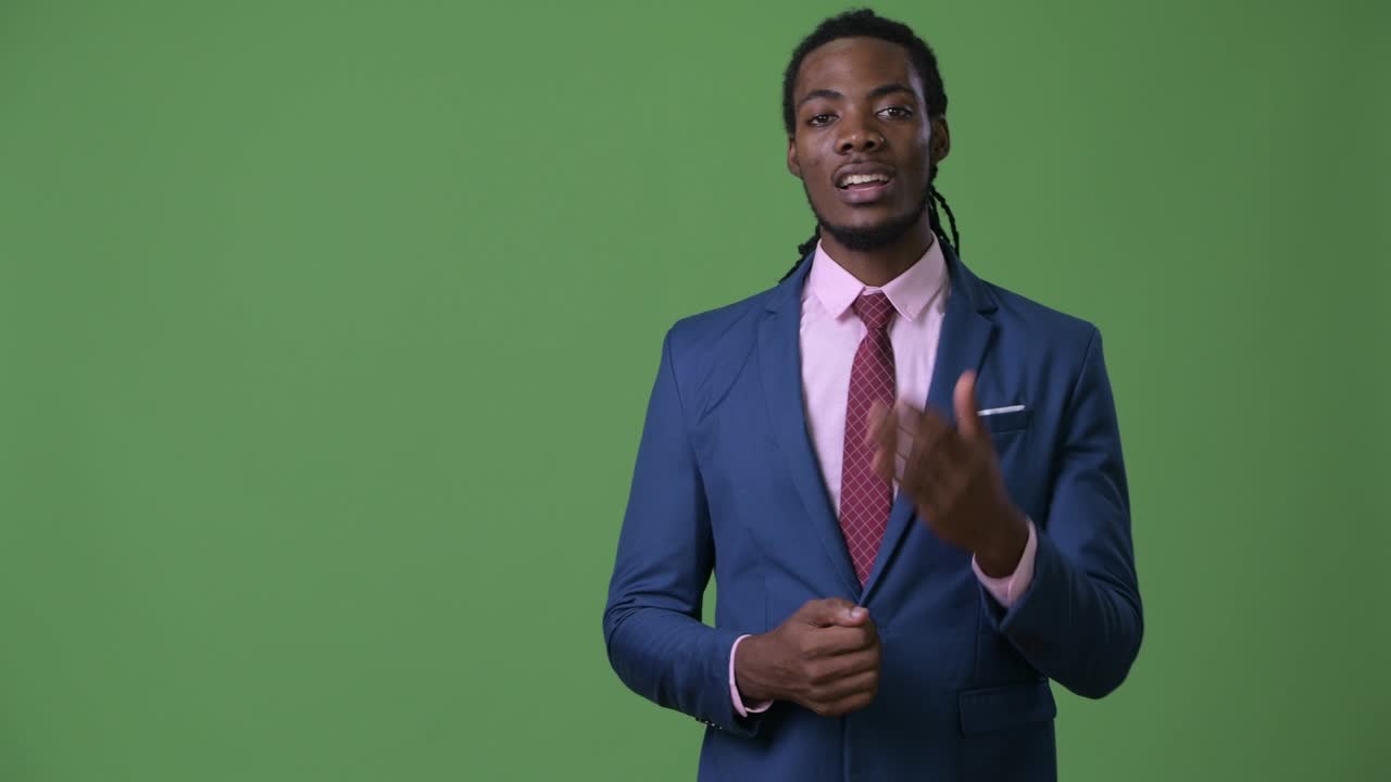 joven empresario africano guapo con dreadlocks contra un fondo verde