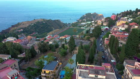 aerial view of green hills carpeted with buildings and the mediterranean sea in the background