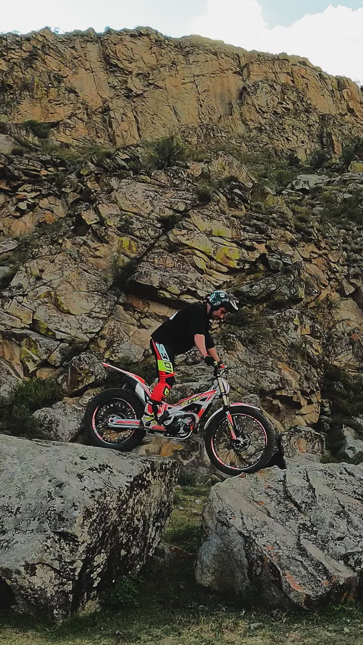 el acróbata de motocicleta muestra un truco en las rocas fpv. un deportista hábil con casco realiza una maniobra de motocicleta en las tierras altas. aficionado a los deportes extremos