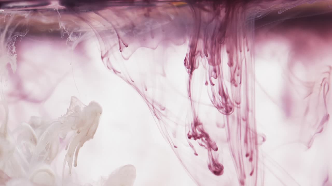 Slow motion video of purple watercolor ink mixing in water against grey background