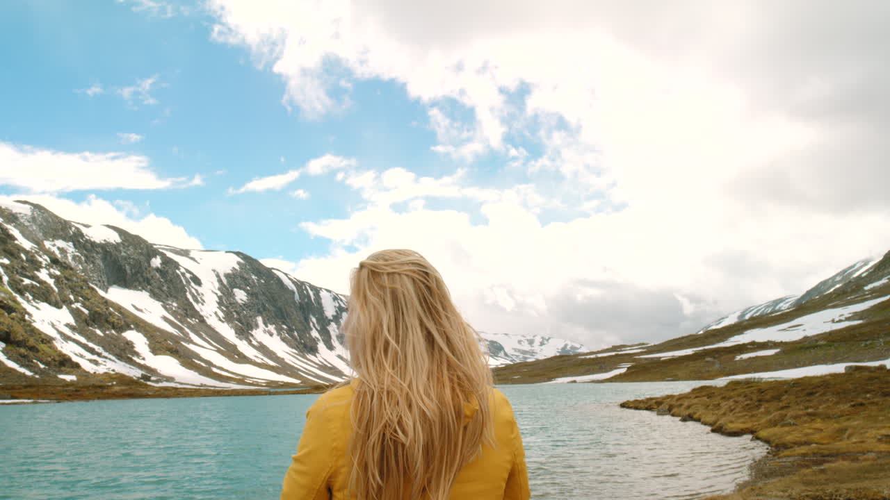 mujer caminando por las montañas junto a un lago