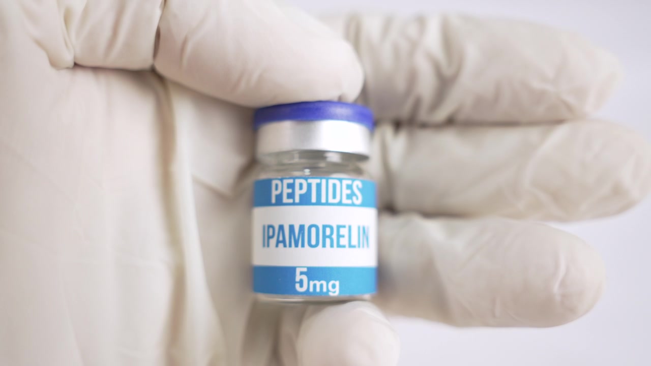Mano guantata di scienziato che tiene una fiala di peptide ipamorelin su sfondo bianco