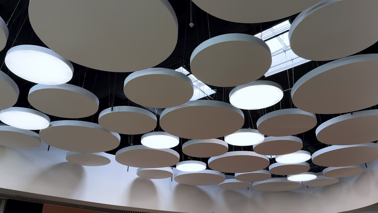 Contemporary ceiling with circles. Bright circular lights hang from a modern ceiling, creating a unique ambiance in a contemporary space