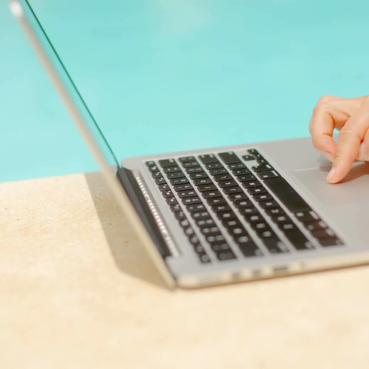 Donna che lavora al laptop a bordo piscina