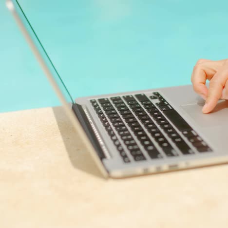 Woman-Working-on-Her-Laptop-in-Swimming-Pool-Area