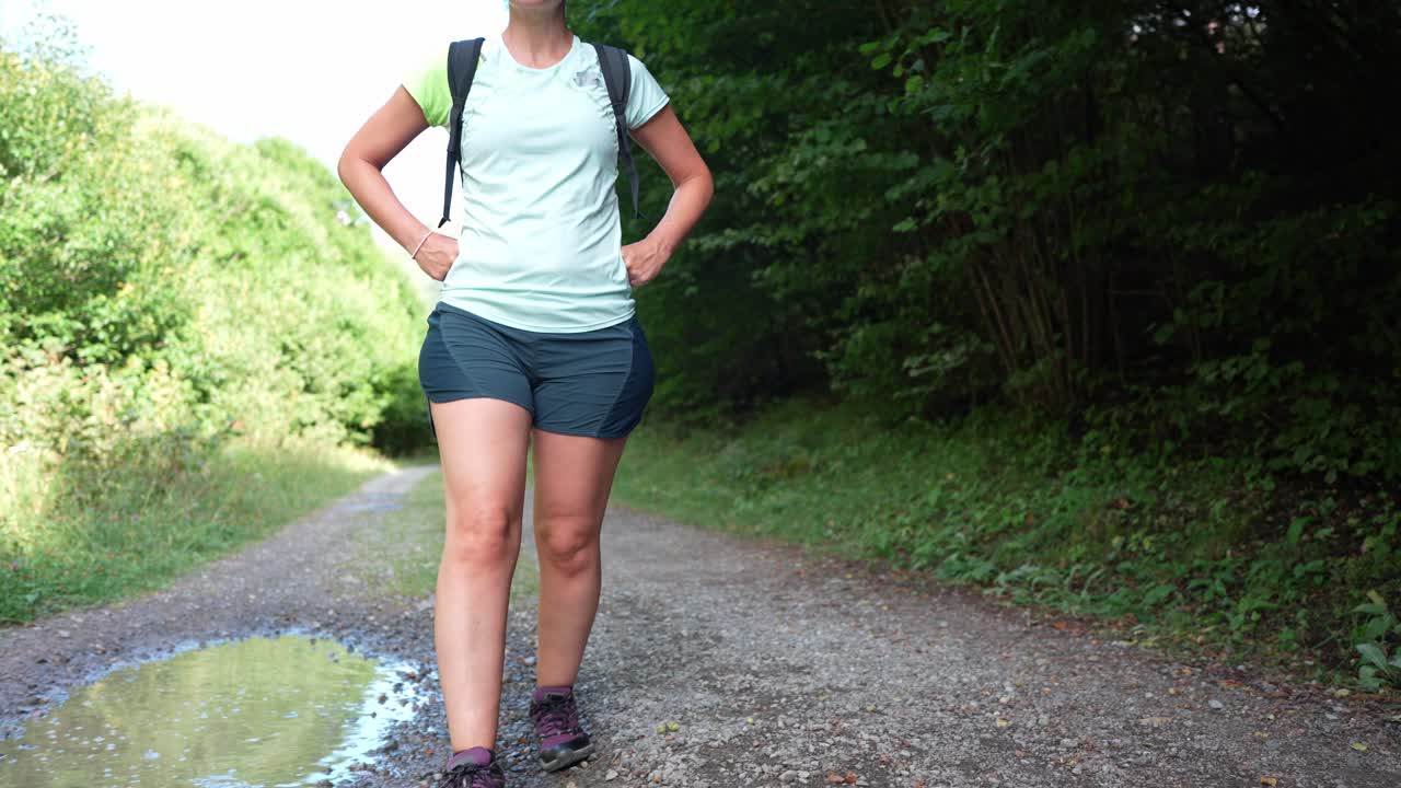 Frau wandert auf einem Schotterweg durch den Wald