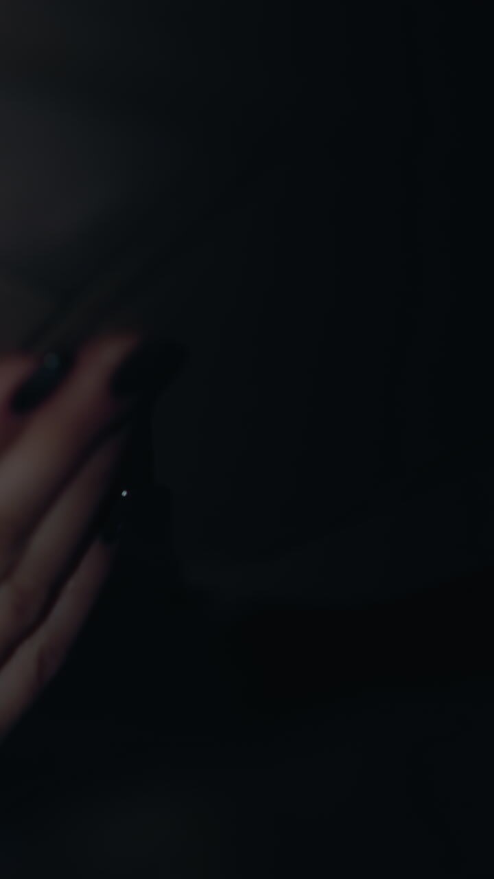 First-person view of a woman turning off the left car light at night. The interior light switch is being turned off, the woman's hand with black painted nails