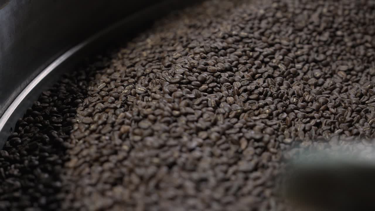 Roasted coffee beans slide along the tray edge during the cooling process