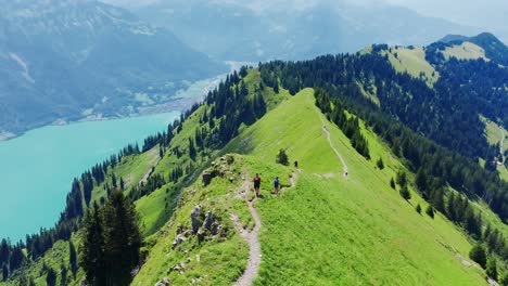 man and woman descend narrow swiss alpine ridge trail with turquoise lake views