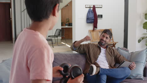 indian father sitting on couch cheering while son holding video game controller